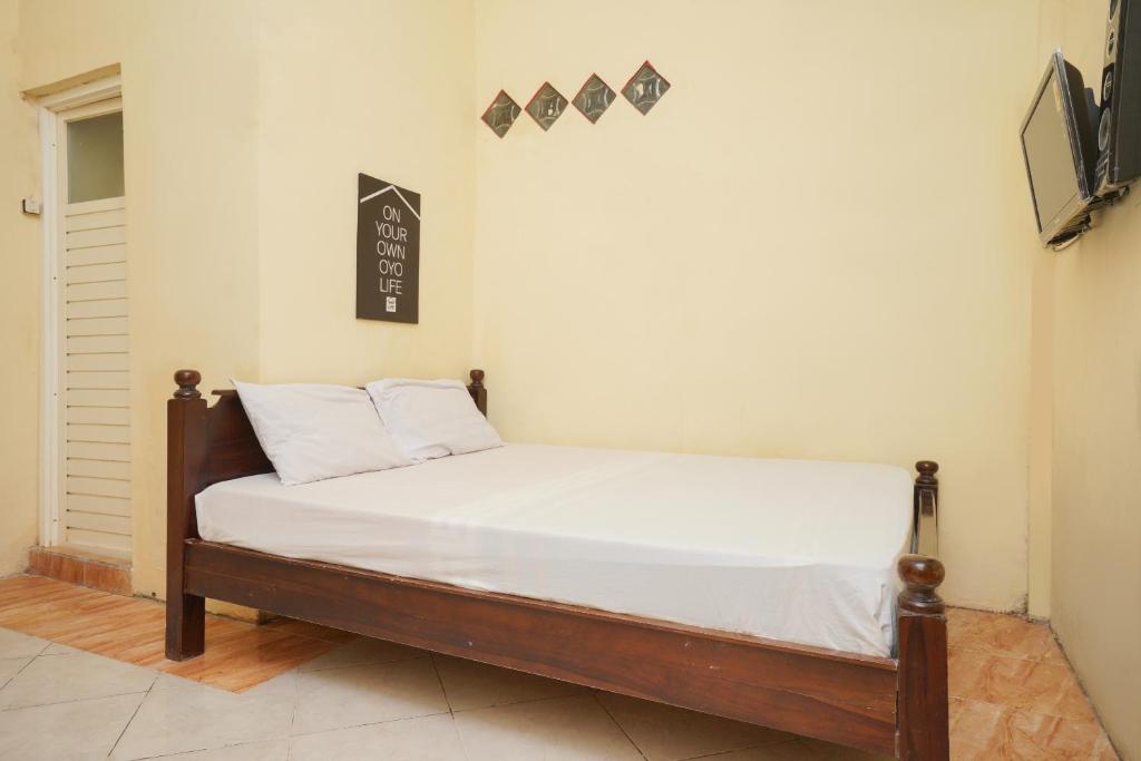 诗都阿佐KoolKost Syariah near T1 Juanda Airport 3的配有白色床单和枕头的宿舍间内的一张床位
