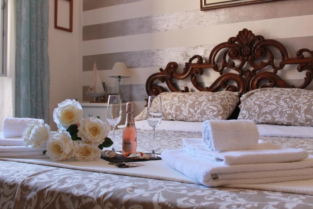 斯培西亚Affittacamere Perla del Prione的一张带毛巾和酒杯的床,床上有鲜花