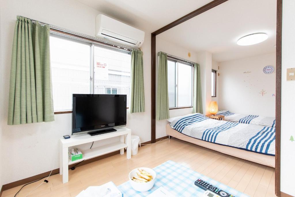 松户市松戸 テイクファイブ 1DK Nomad松戸宿056的一间卧室配有一张床和一张桌子上的电视