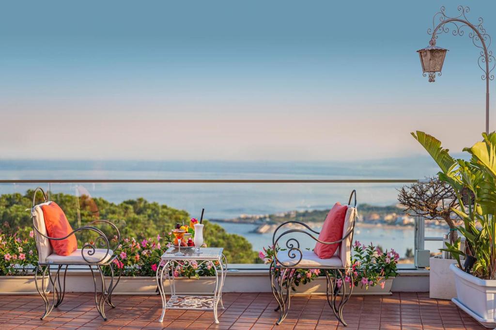 陶尔米纳欧陆酒店的美景阳台配有两把椅子和一张桌子
