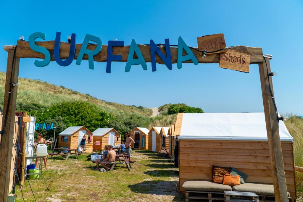 弗利兰Surfana Beach camping hostel Bed & Breakfast Vlieland的院子里一群小房子,上面有标志