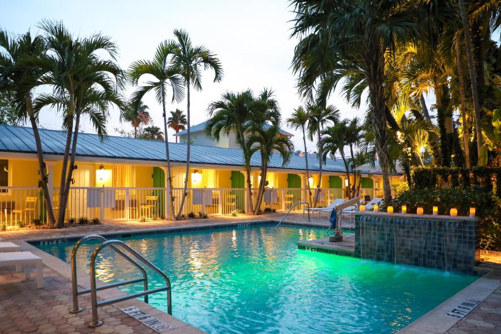 基韦斯特Almond Tree Inn - Adults Only的一座棕榈树游泳池和一座建筑