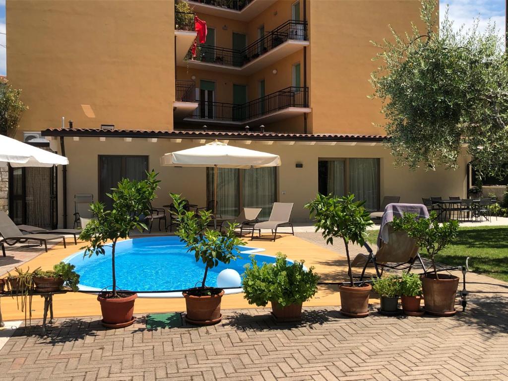 加尔达Appartamenti Villa Dall'Agnola的一座建筑前的游泳池,里面设有植物和遮阳伞