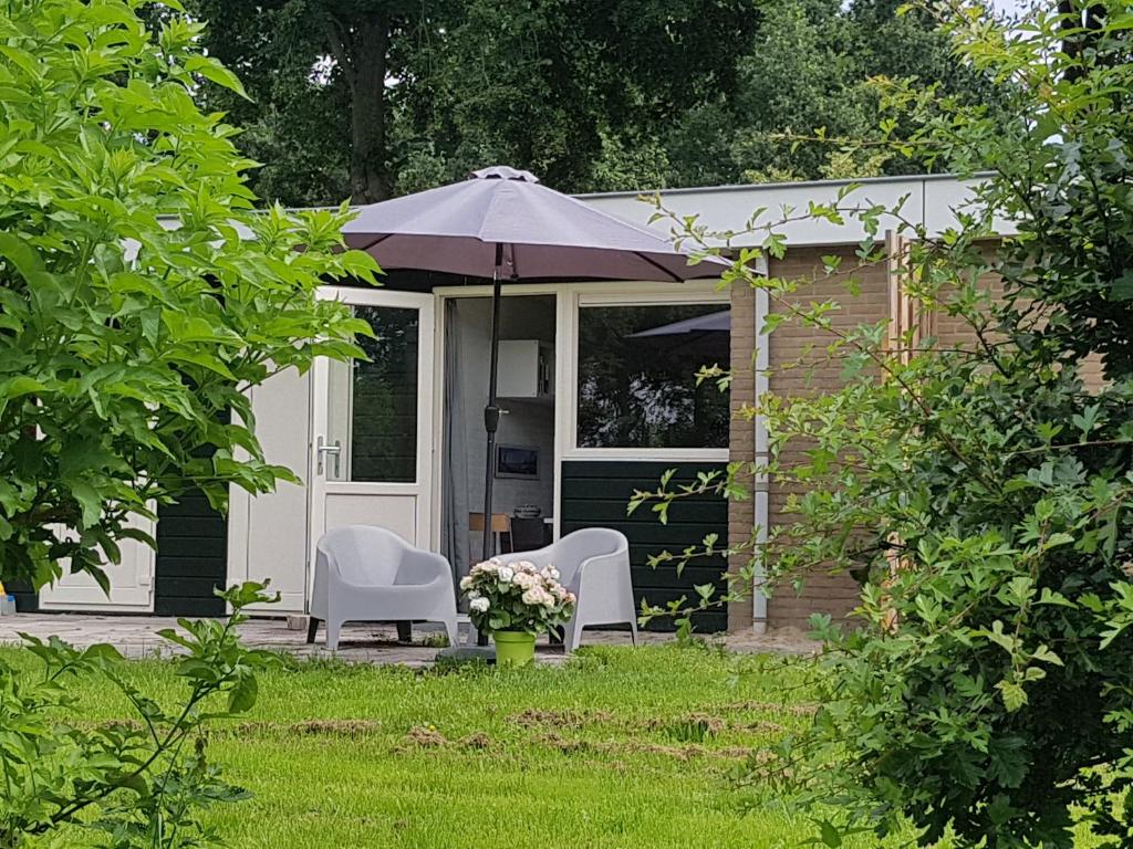 AnnerveenschekanaalDrenths Landgoed, Lekker uit的院子里有两把椅子和一把伞的房子