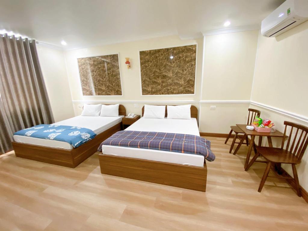 海防Đình Vũ 3 Motel的酒店客房设有两张床和一张桌子。