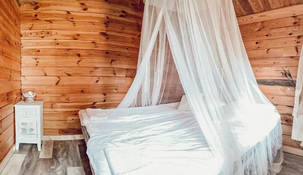 NurmePruuli Puhkeküla的配有蚊帐的木制客房内的一张床位