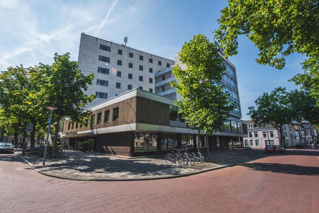 格罗宁根Flonk Hotel Groningen Centre, BW Signature Collection的一座树木繁茂的城市街道上的大型建筑
