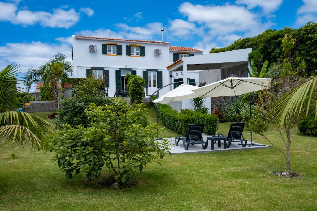 坎普自由鎮Casa da Quinta的白色的房子,配有两把椅子和一把伞
