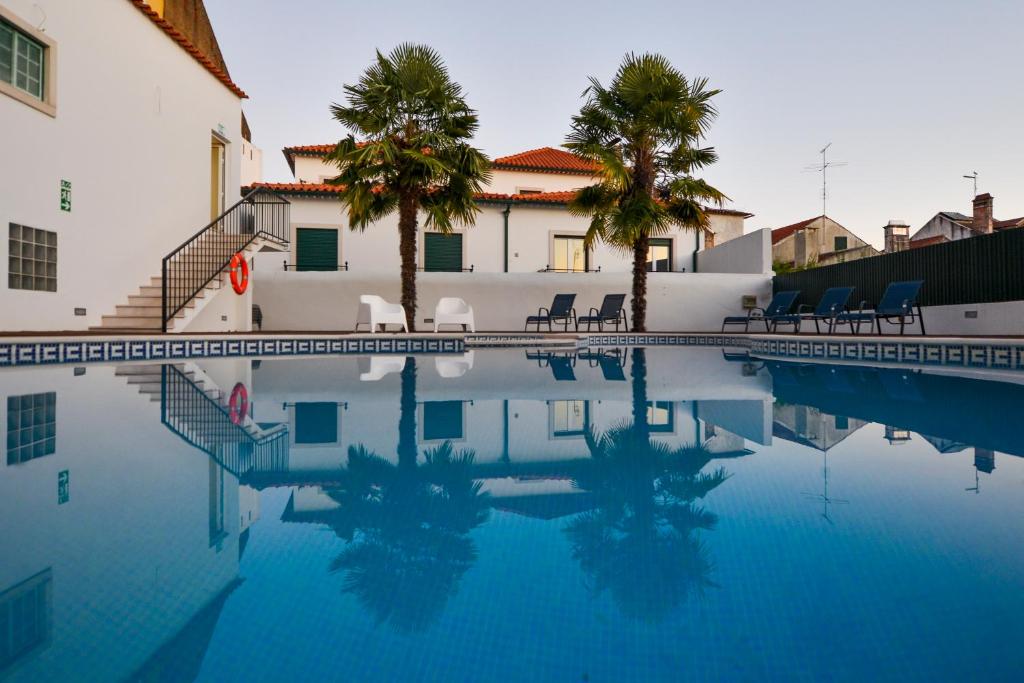 托马尔O Paço - exclusive accommodation的一座游泳池,旁边是椅子和棕榈树