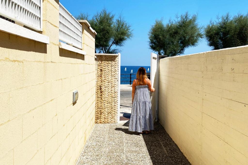 焦维纳佐La Rotonda - Casa vacanze的站在一堵墙上看着海洋的女人