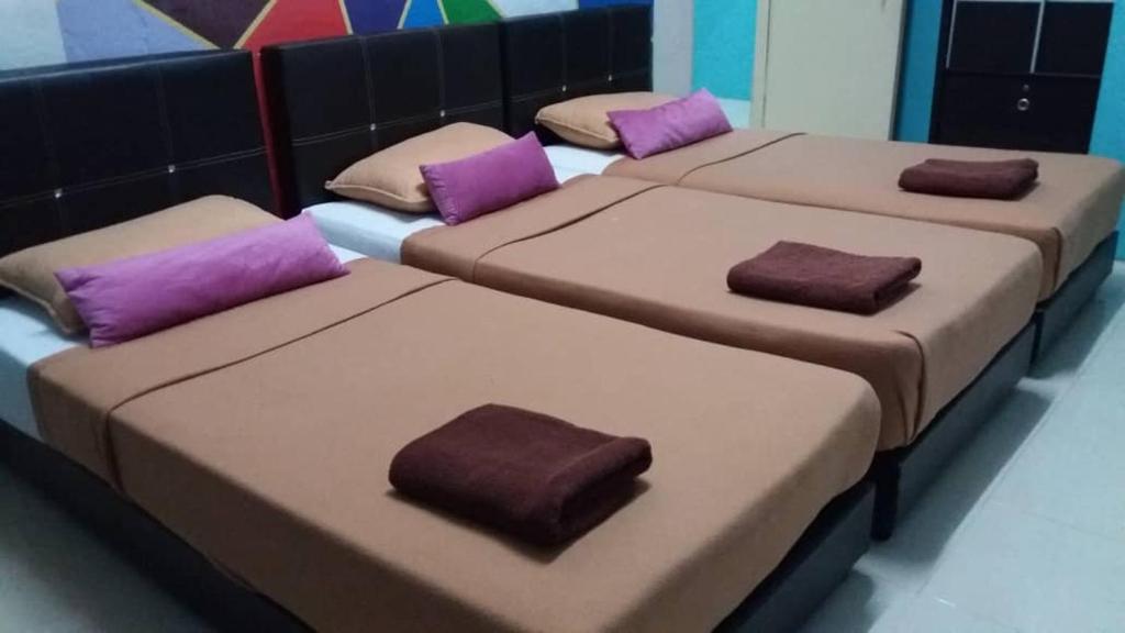 PakaManja Inn, Paka的客房内的三张床,配有紫色枕头
