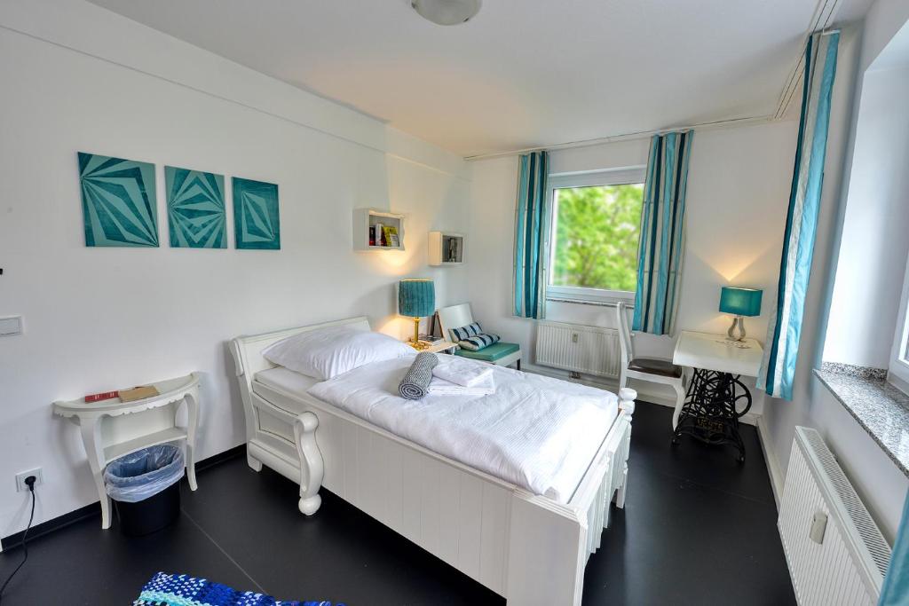 埃森Hostel am Niederfeldsee的卧室配有白色的床和书桌