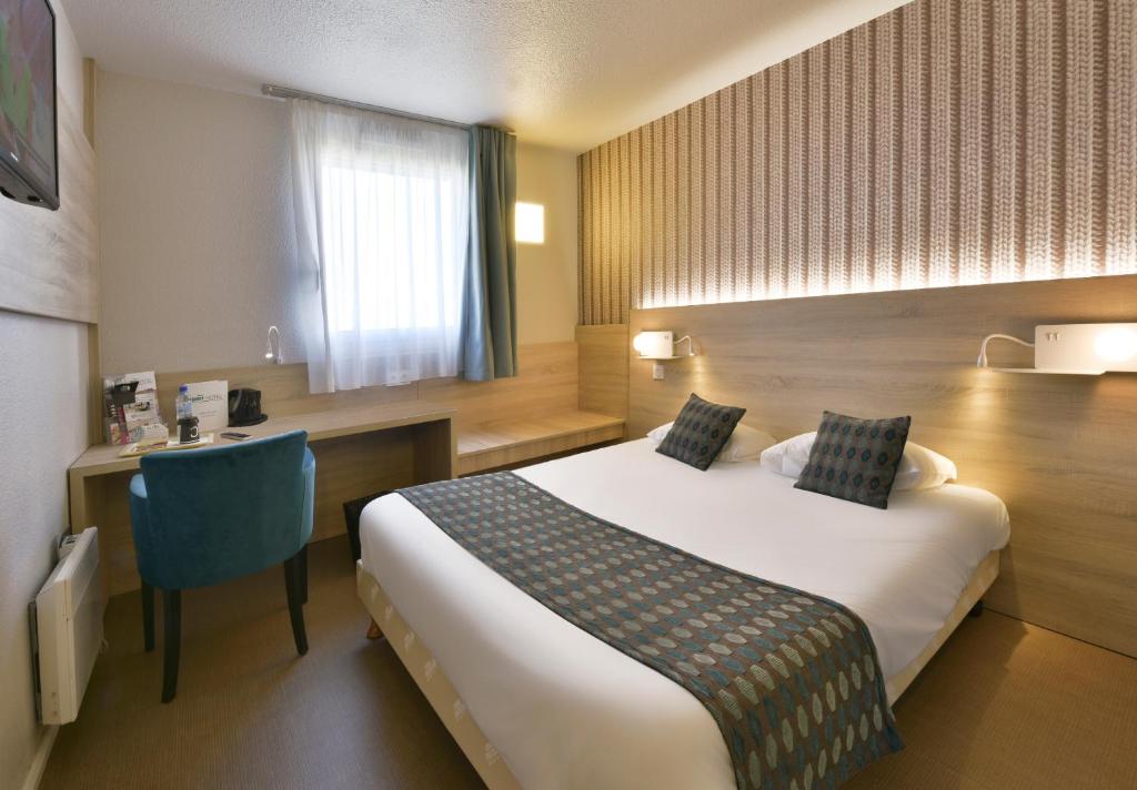 朗迪维西奥Brit Hotel Landivisiau的配有一张床和一张书桌的酒店客房