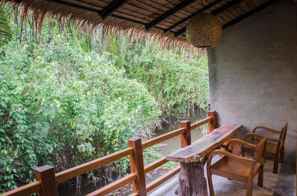 素叻鲁恩泰奈班盘萨克度假酒店的门廊配有木桌、椅子和树木