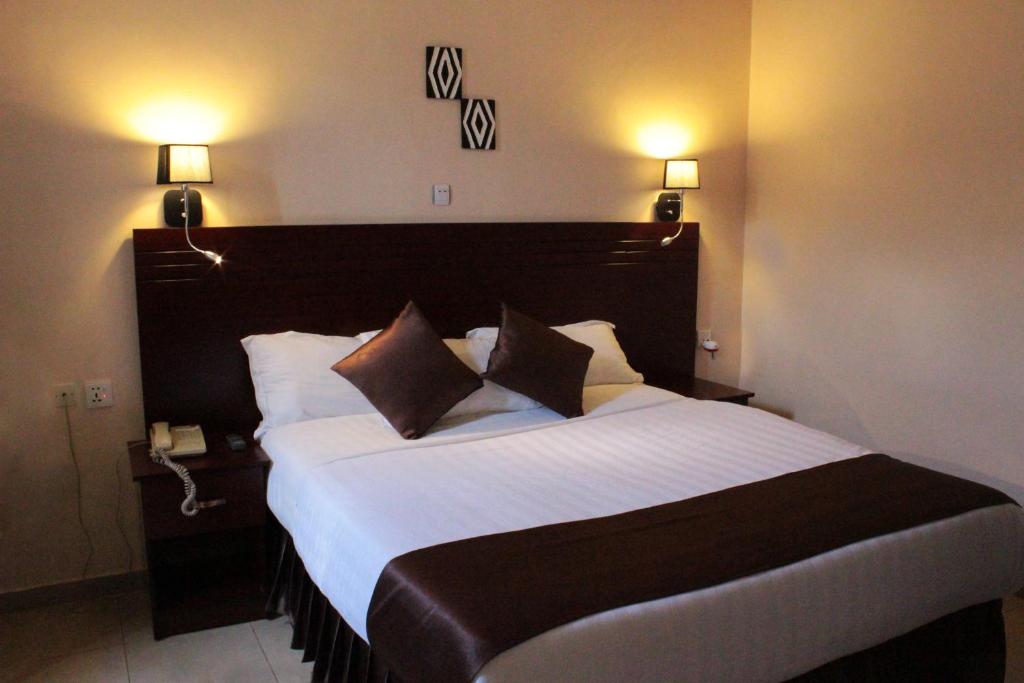 RwamaganaDereva Hotel Rwamagana的一张大床,位于酒店带两盏灯的房间