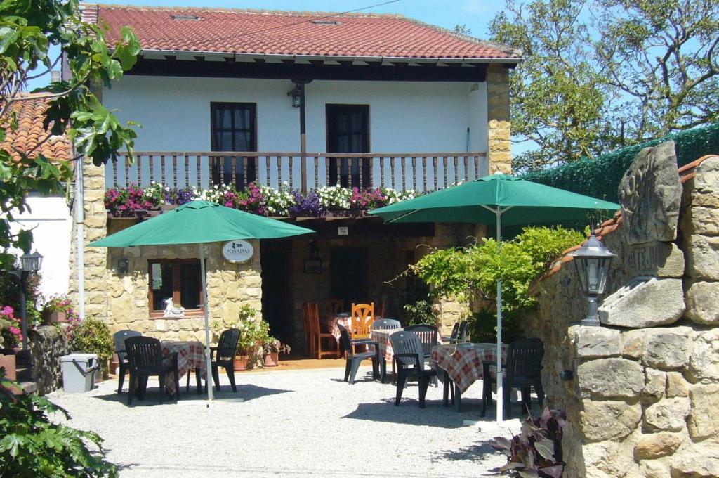 Valdaliga 波萨达艾尔泰胡酒店的房屋前设有带桌子和遮阳伞的庭院。