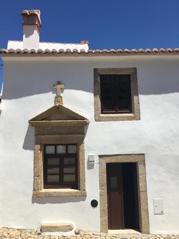 马尔旺Casa do Sétimo Passo的白色的建筑,有两个窗户,一个十字架