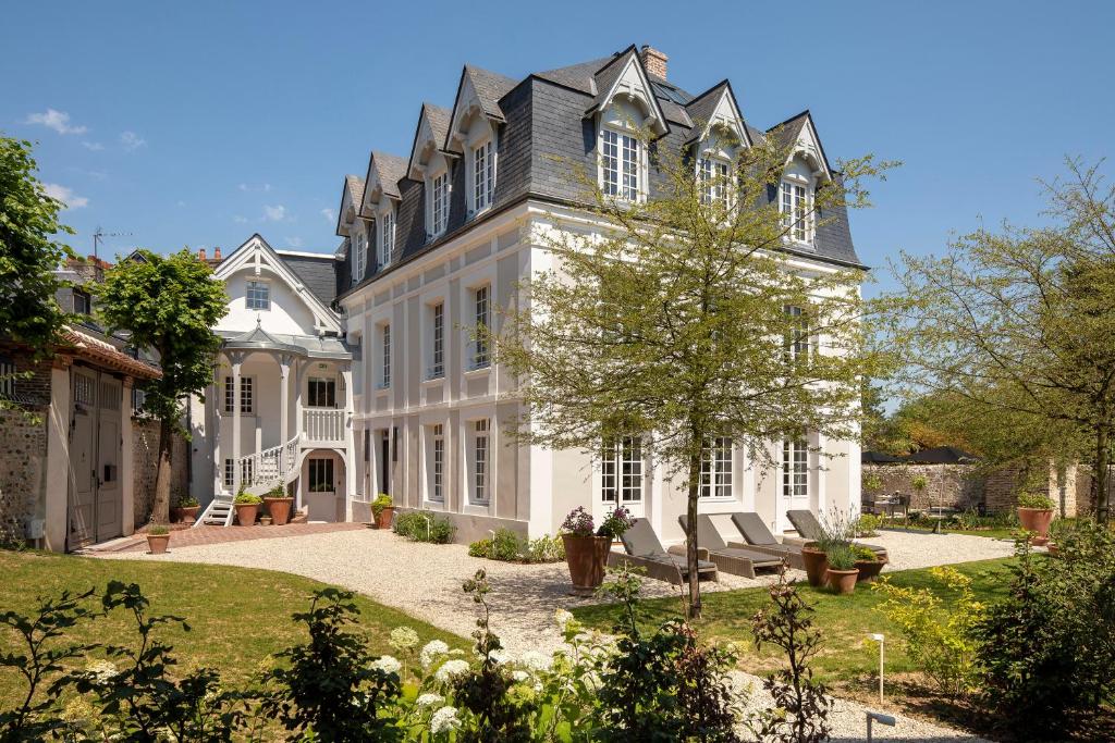 翁弗勒尔Hôtel Saint-Delis - La Maison du Peintre - Relais & Châteaux的一座带椅子的庭院的白色大房子