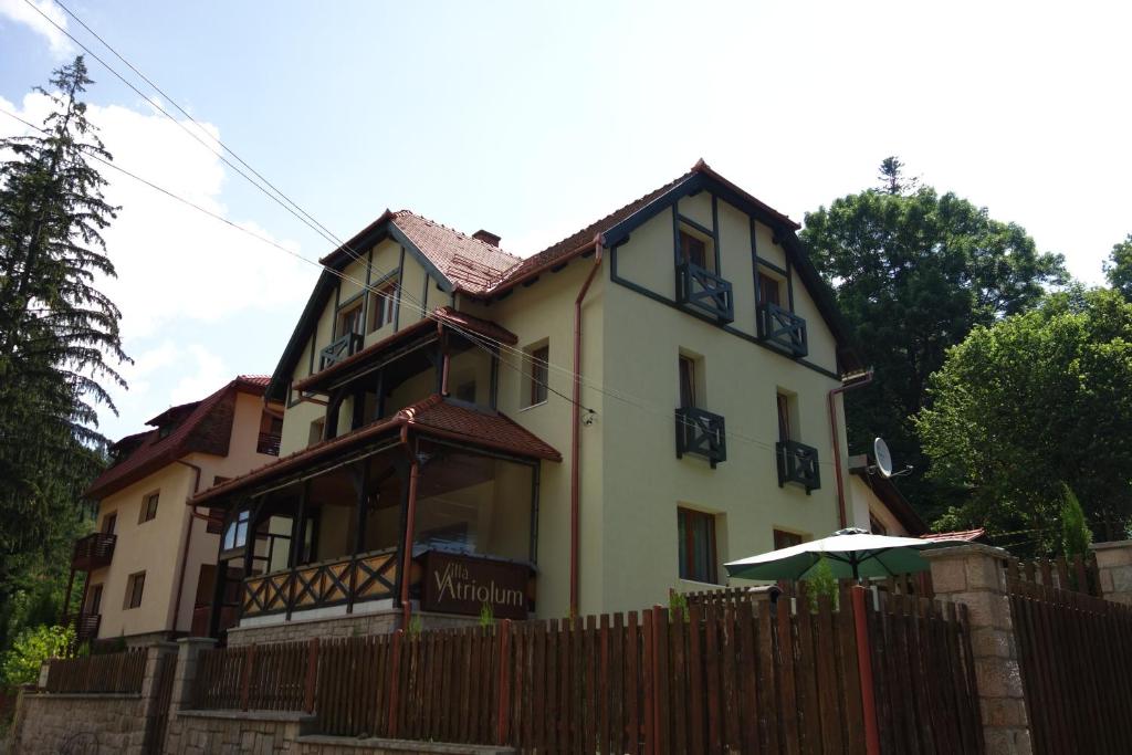 伯伊莱图什纳德Villa Atriolum的黄色房子,带栅栏和雨伞