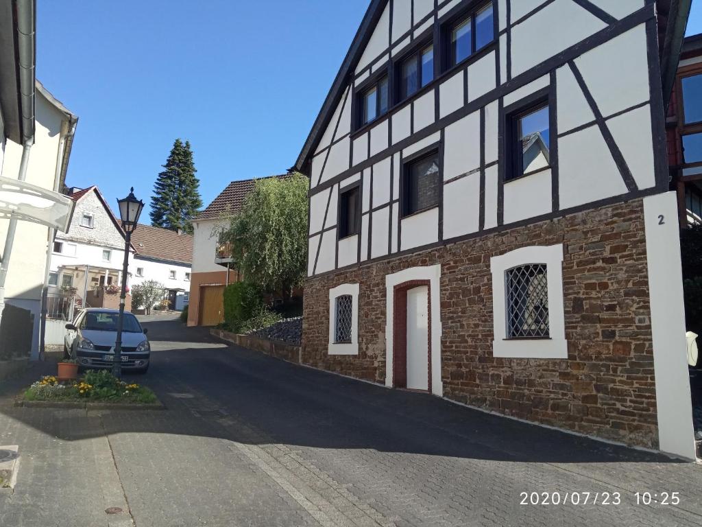 温德克Ferienwohnung Windecker Ländchen的黑色和白色的建筑,有一辆汽车停在街上