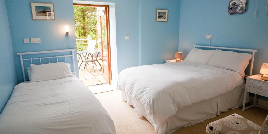 利马瓦迪Ballyhenry House and Apartments的一间蓝色的卧室,配有两张床和一个庭院