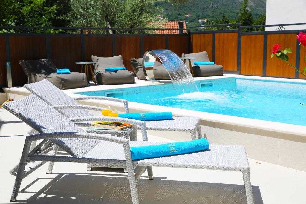 科托尔阿尔奇马酒店的一个带两把椅子的游泳池和一个喷泉