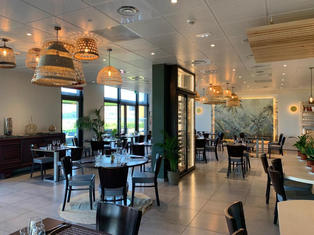 Saint-Symphorien-sur-CoiseHôtel L'Horizon - Restaurant La Fougassette的用餐室配有桌椅和吊灯。