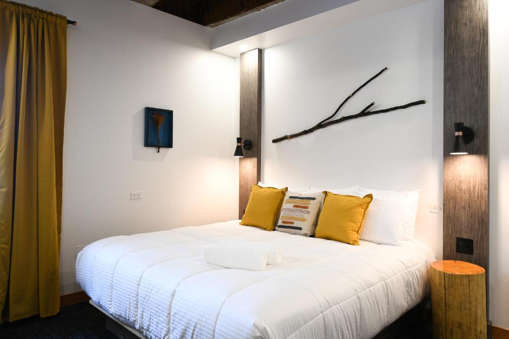 魁北克市Hotel Le Bloc的卧室配有一张带黄色枕头的大型白色床。