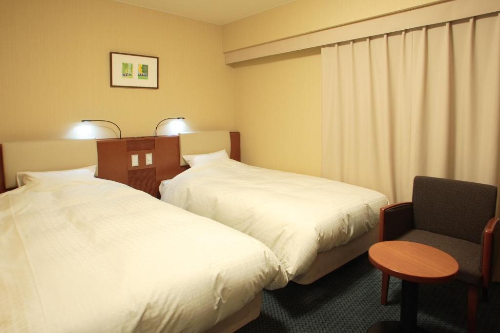 仙台仙台国分钉微笑酒店的酒店客房,配有两张床和椅子