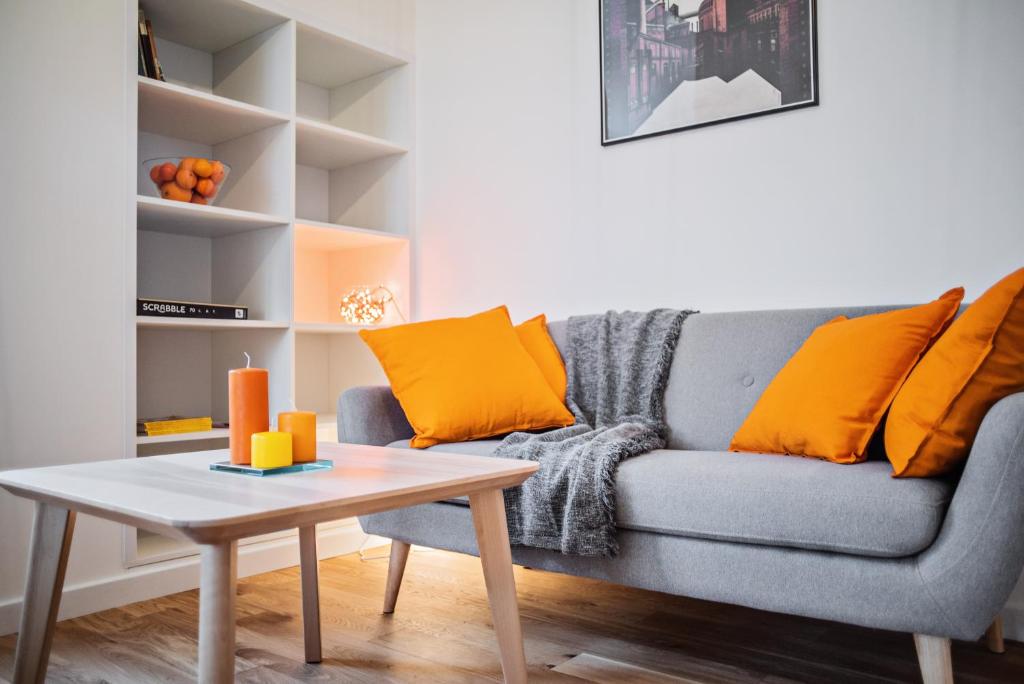 波兹南Best INN Poznań Apartament Orzeszkowej的客厅配有带橙色枕头的灰色沙发