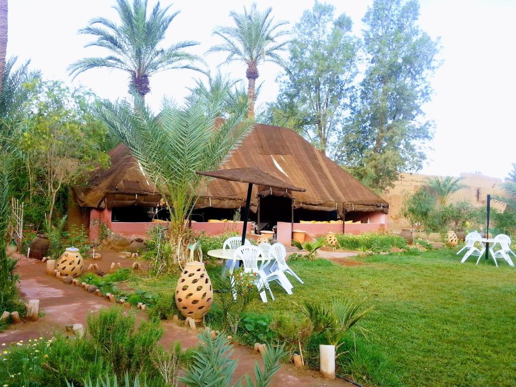 TamgroutParadise in the desert of Morocco的小屋配有椅子和桌子,棕榈树