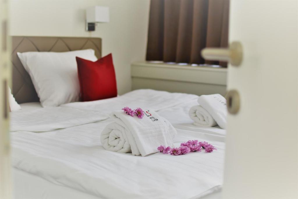 巴尼亚卢卡Hotel Slavija Banja Luka的白色的床,上面有毛巾和紫色的鲜花