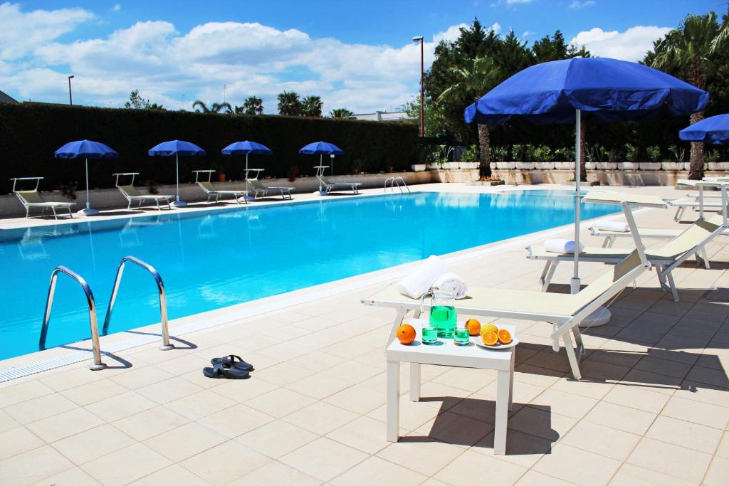 托里德欧索奥斯萨伦托公寓的游泳池配有椅子、桌子和遮阳伞