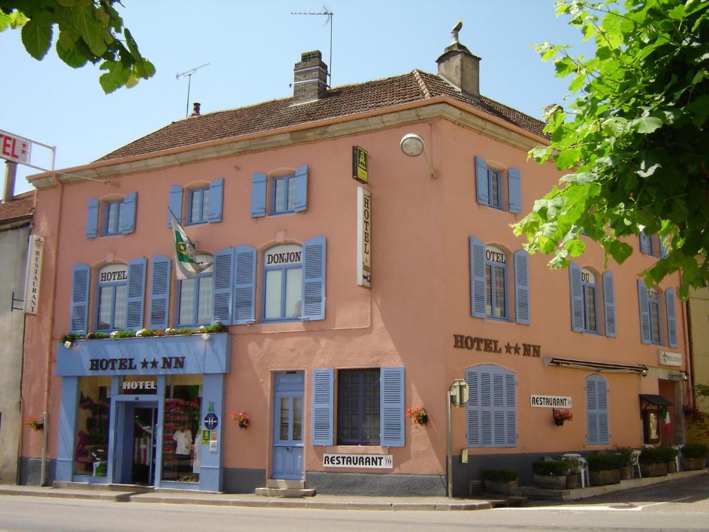 Champlitte-et-le-Prélot东荣酒店的街道上一座粉红色的建筑,上面有蓝色百叶窗