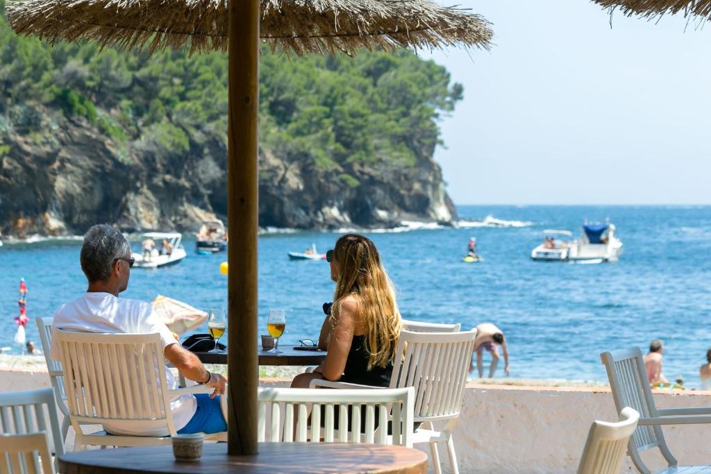 罗萨斯卡拉蒙特基酒店的坐在海滩桌子上的男人和女人