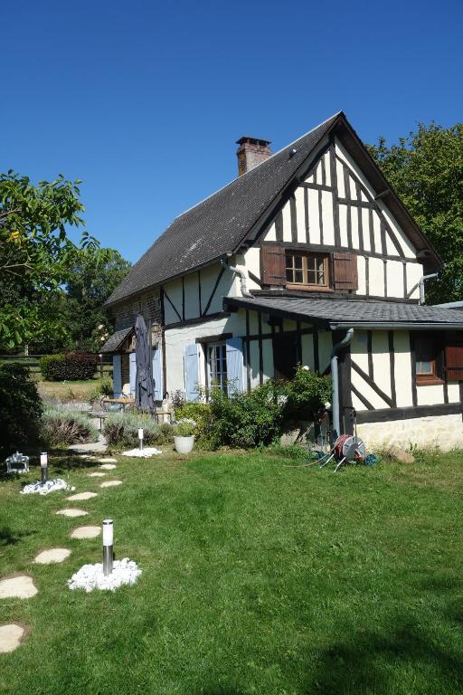 Le cottage du Coudray, gîte avec chalet sauna的一座白色和黑色的大房子,有院子