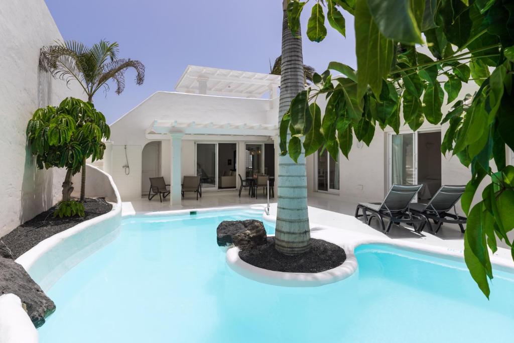 科拉雷侯Bahiazul Villas Corralejo by Vreagestion的一座房子前面的游泳池,上面有棕榈树