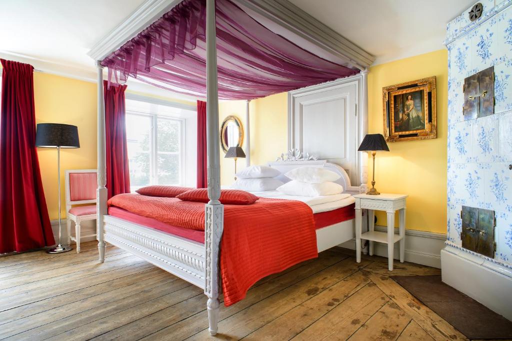 斯德哥尔摩赫尔斯顿斯马尔加德酒店的一间卧室配有一张带红色毯子的天蓬床