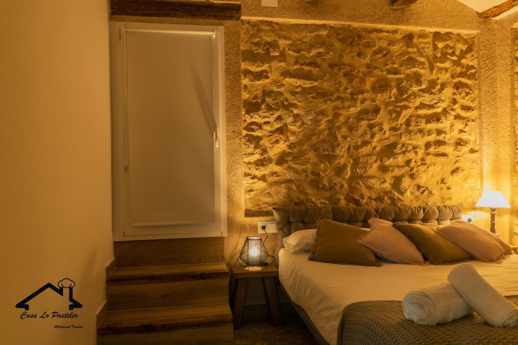 RoquetasCASA LO PASTELER的一间卧室设有一张床和石墙