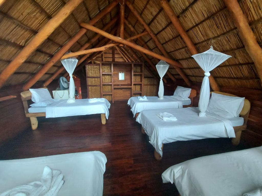 ChizavaneEast Africa Safaris的茅草房内设有四张床