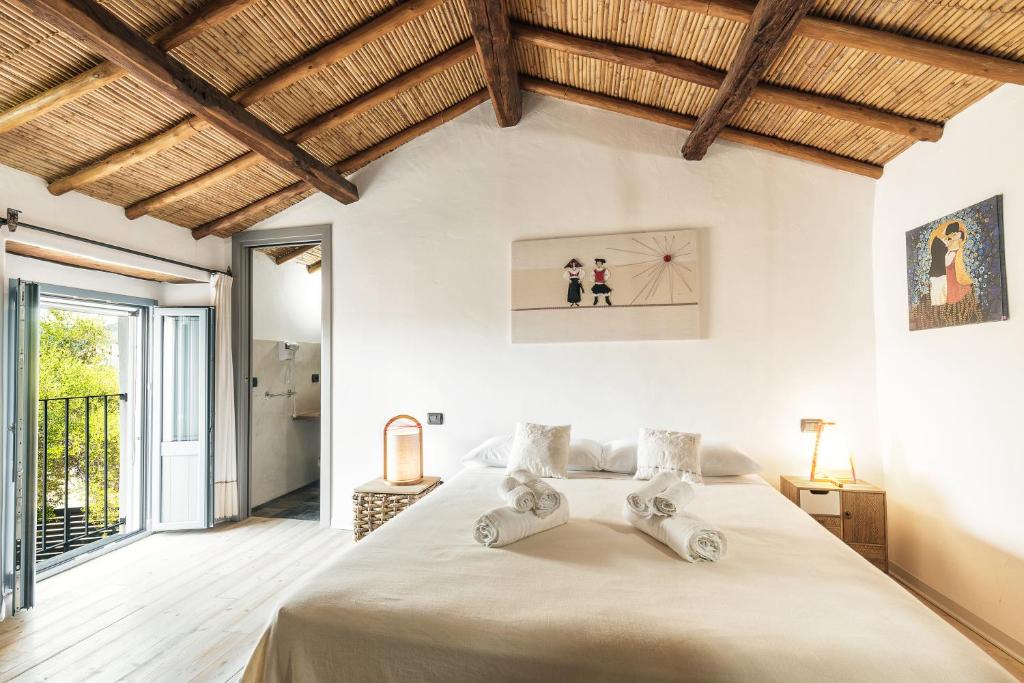 洛特佐拉伊Sa Crai B&B - Sardinian Experience的一间带一张大床的卧室,位于一个拥有木制天花板的房间