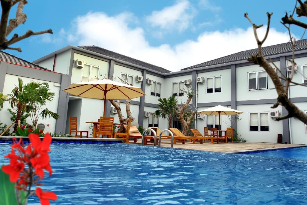普拉亚嘉逸皇冠BIL酒店的一个带游泳池、椅子和遮阳伞的度假村