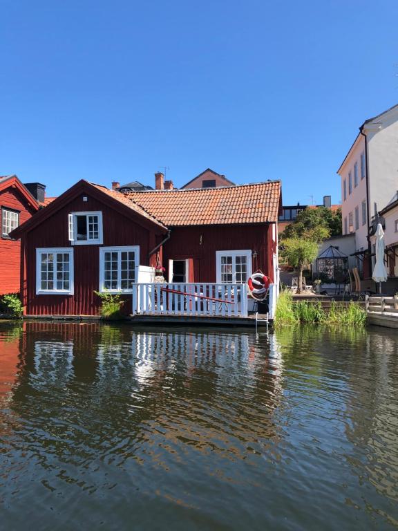 埃斯基尔斯蒂纳Stugan med Bryggan i Gamla Staden的水面上的房子,前面有船