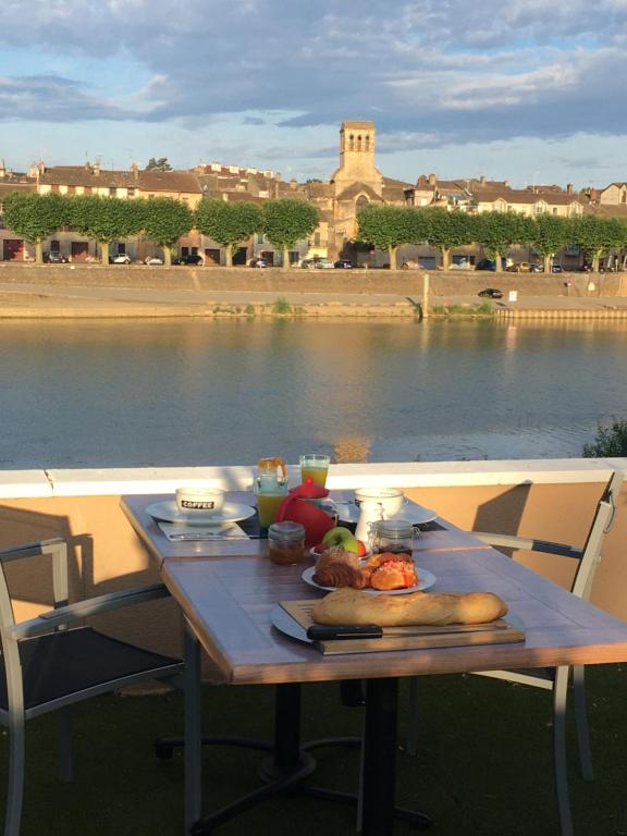 图尔尼Domaine les jardins de la Saône的水体旁的桌子上放着食物