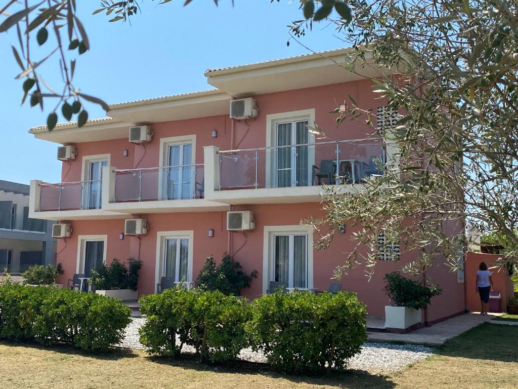斯达林Megali Beach Nikos的一座粉红色的房子,前面有一个女人