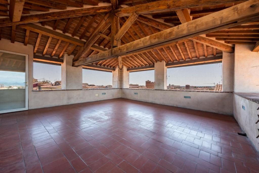 比萨Nella Torre del Poschi Penthouse with Roof Terrace的空空的客房设有木制天花板和大窗户。