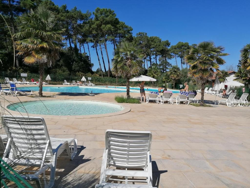 翁德尔T2 Antigua Ondres plage avec piscine et tennis的一个带桌椅的游泳池,棕榈树