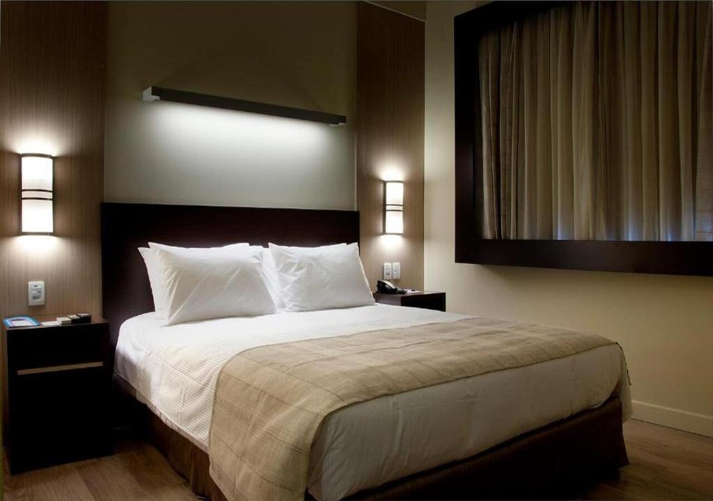 阿雷格里港Master Cosmopolitan Moinhos de Vento的卧室配有带白色枕头的大床