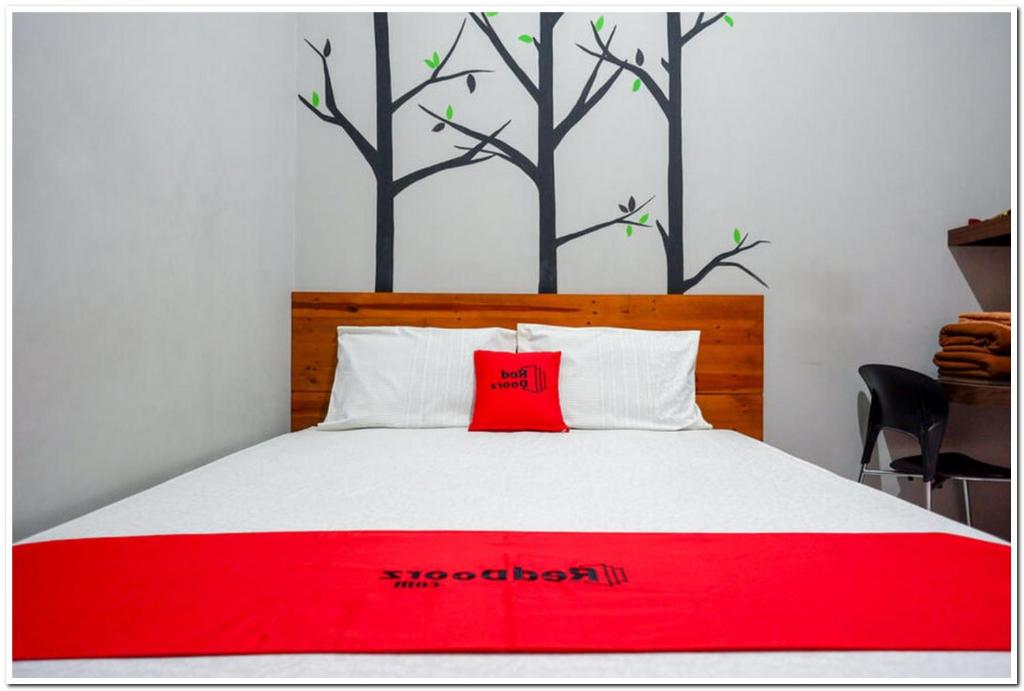 日惹RedDoorz near Jogja Expo Center 2的墙上树木的床上红色枕头