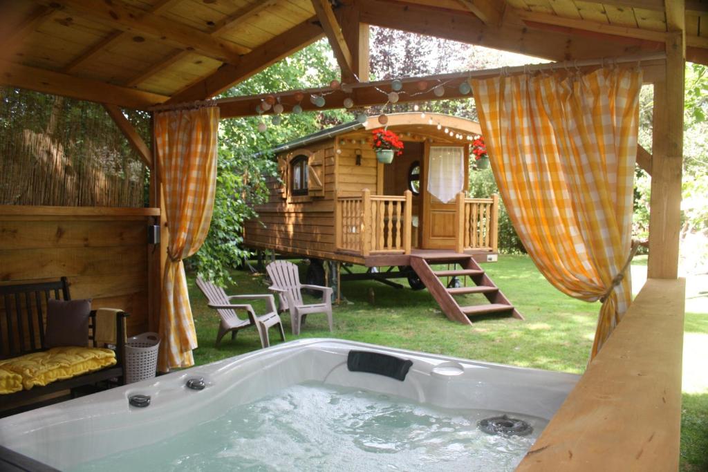 BeurlayLa Roulotte d'Emilie et son jacuzzi privé的后院的热水浴池,有树屋